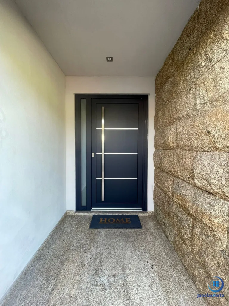 Porta de entrada moderna integrada na fachada em pedra da moradia